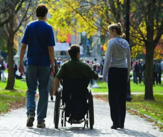 A photo of 3 people exploring a park, one person uses a wheelchair