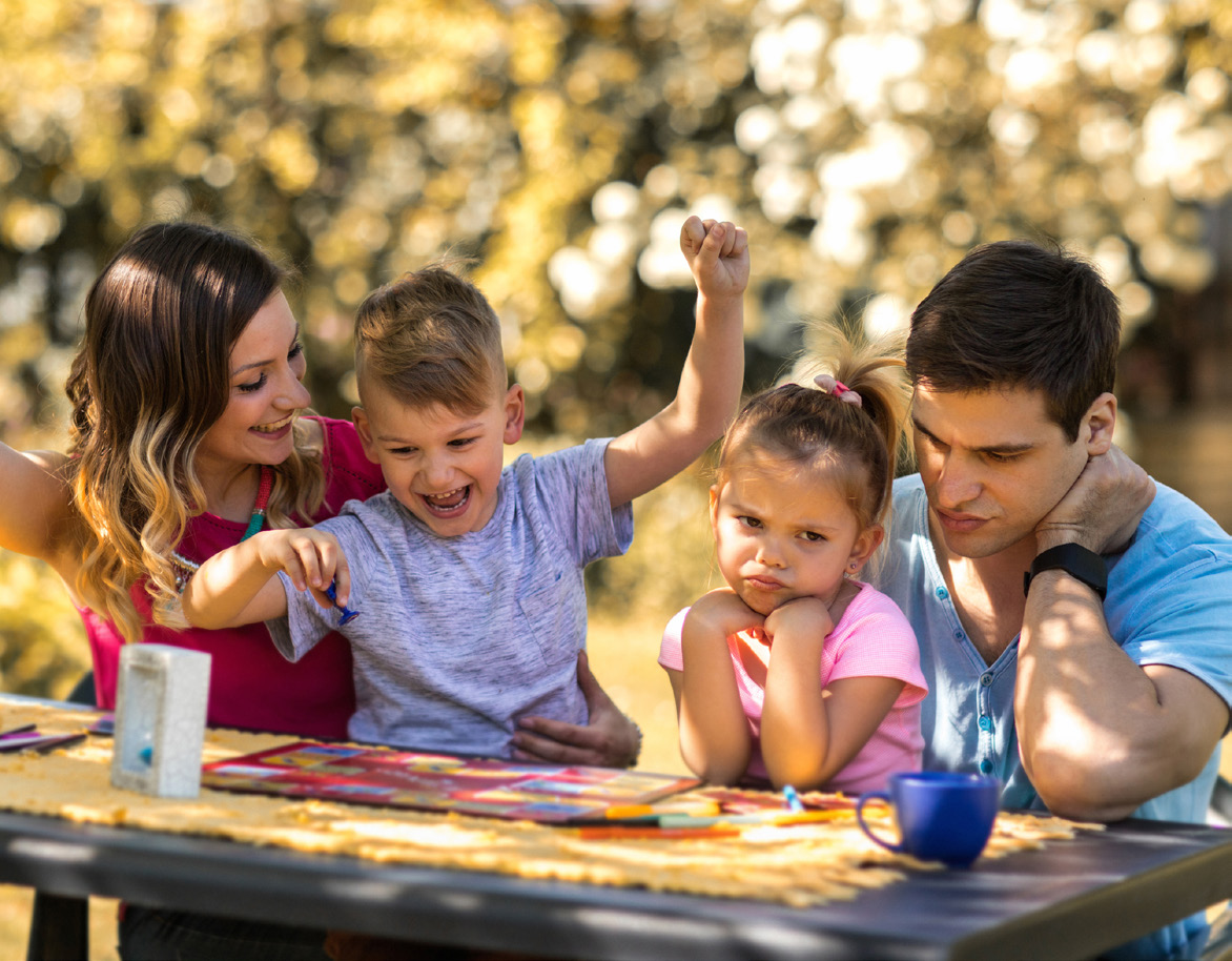 a photo of a family playing a board game outside on a picnic table